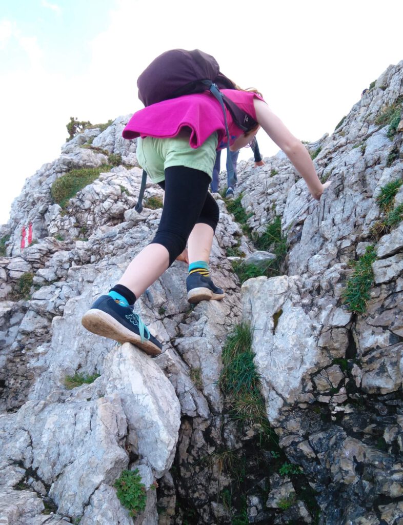 Foto einer am Felsen aufsteigenden Person.