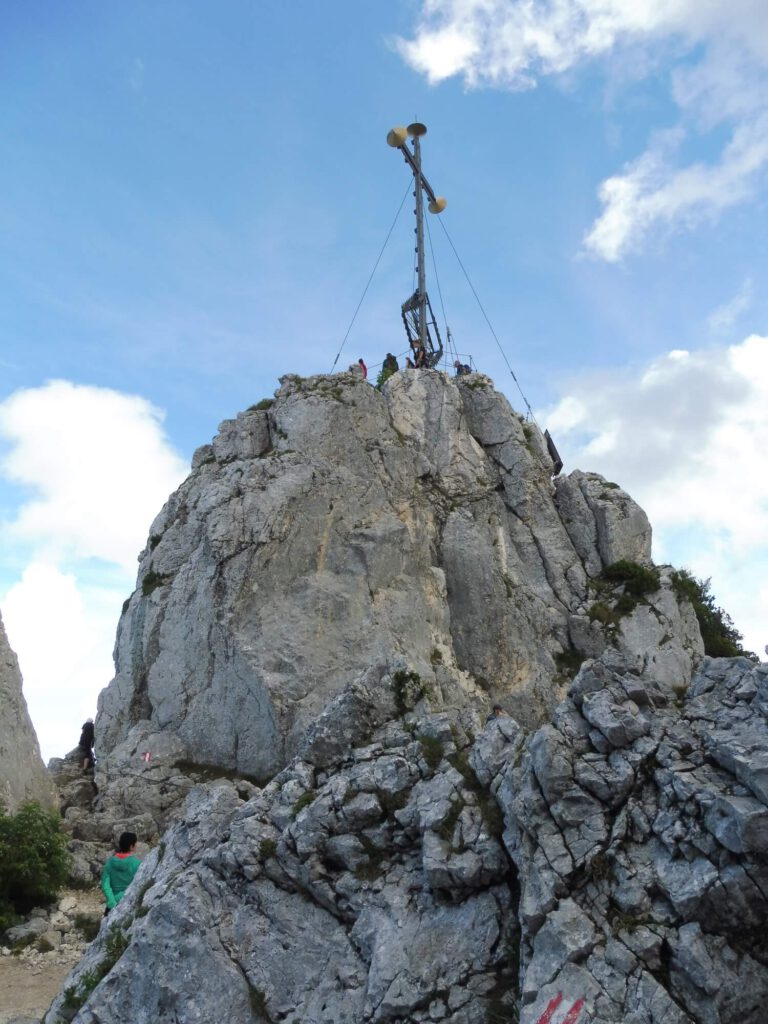 Foto eines Kreuzes auf einem Berggipfel aus der näheren Perspektive.