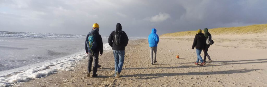 Foto einer Männergruppe von hinten am Meer.