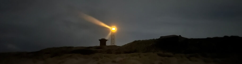 Foto Leuchtturm bei Nacht und wolkenverhangenem Himmel