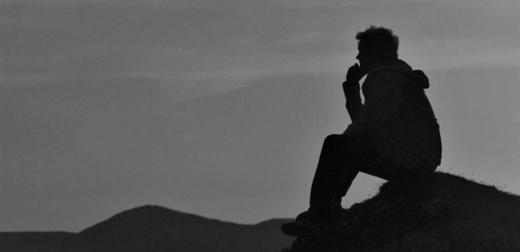 Foto Mann nachdenklich auf Berg sitzend schwarzweis von Pixabay