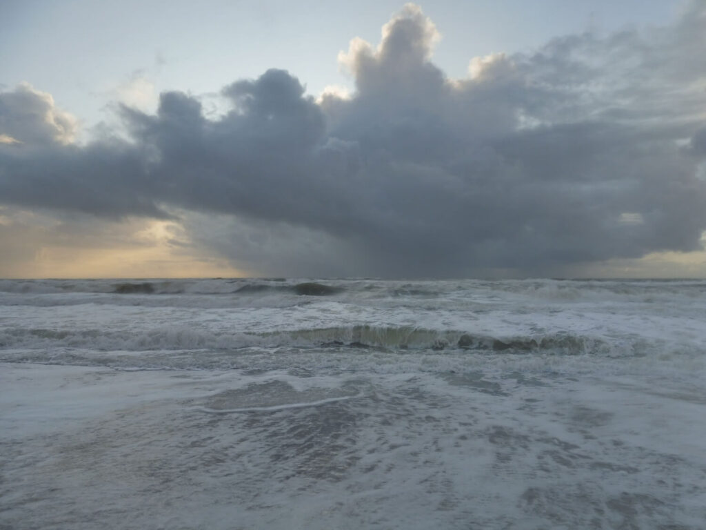 Bild einer einzelnen Sturmwolke, die am Horizont durch Regen das Meer berührt und sich nach oben trichterförmig ausweitet.