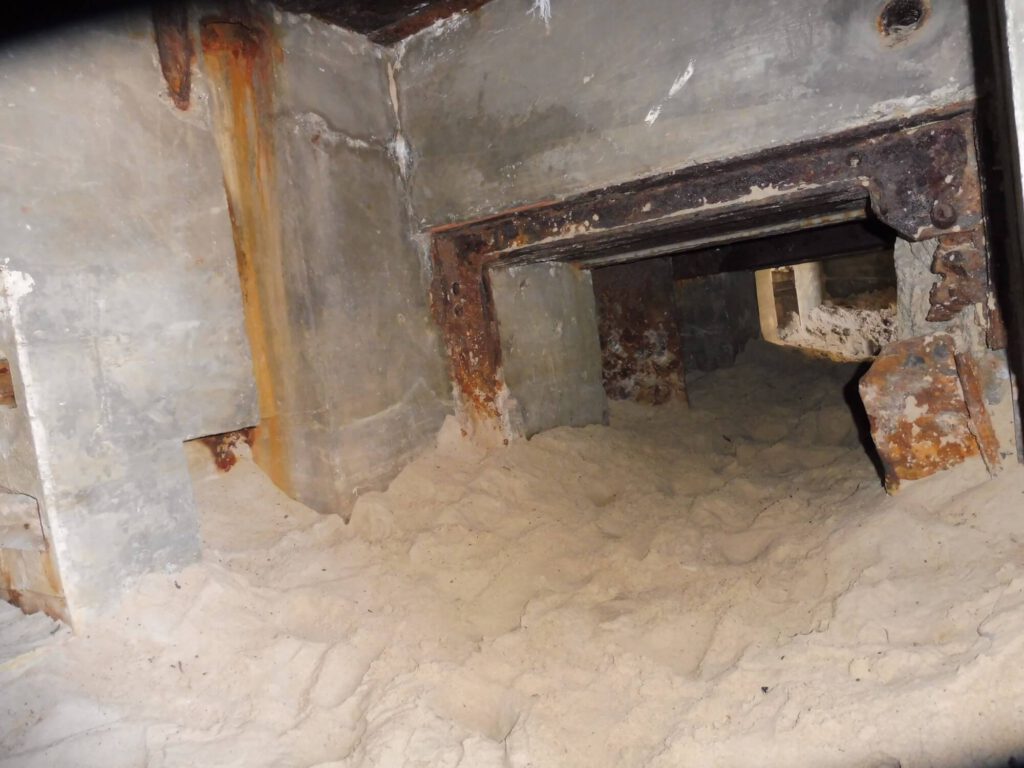 Ein historischer Bunker am Strand von Dänemark von innen. Was ehemals Gänge und Räume waren, ist voll mit Sand.