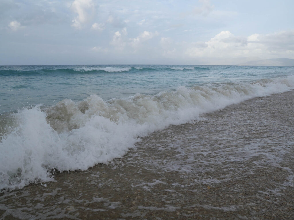 Aufnahme einer heranrollenden und brechenden Welle am Strand.