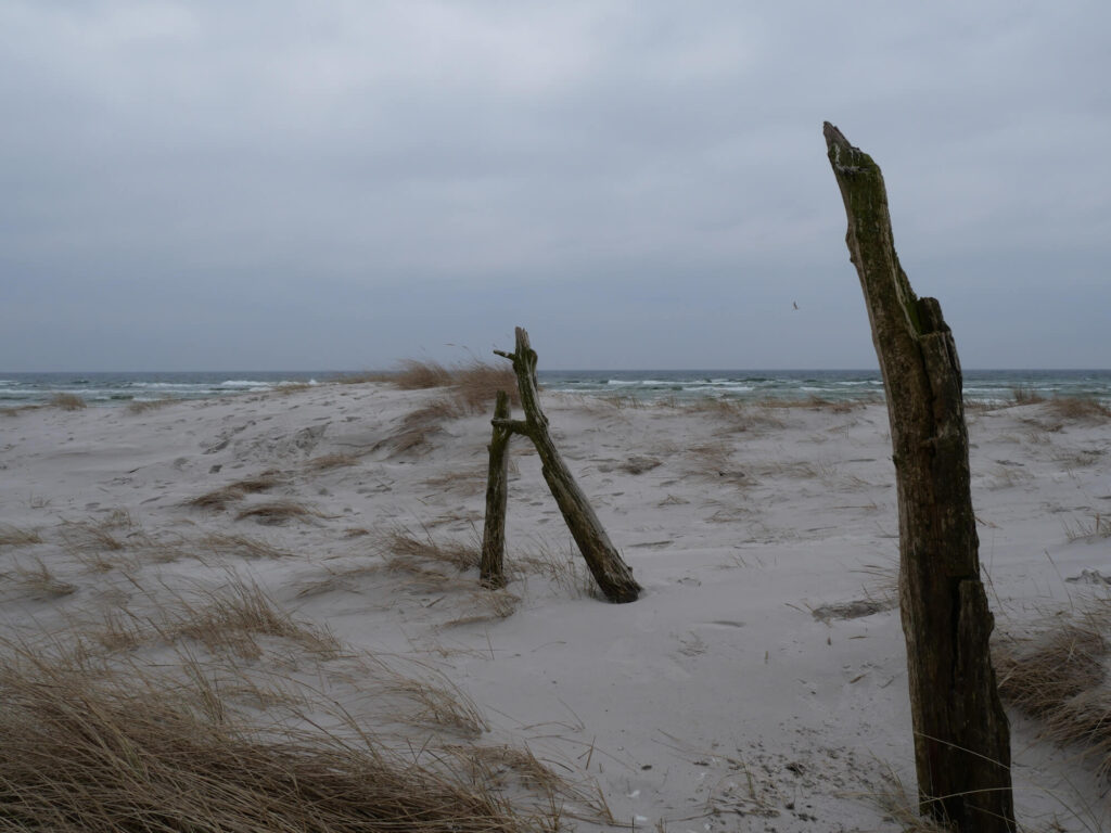 Mein Kraftort das Meer: Strandaufnahme mit einer Sanddühne im Vordergund und dahinter das Meer.