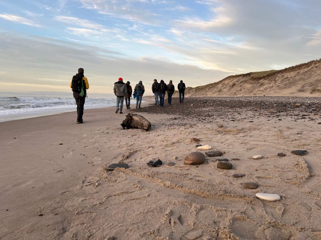 Männer während ihrer Männerauszeit am Meer, im Vordergrund das Rad der Jagd nach Udo Schroeter ('Bin am Meer').